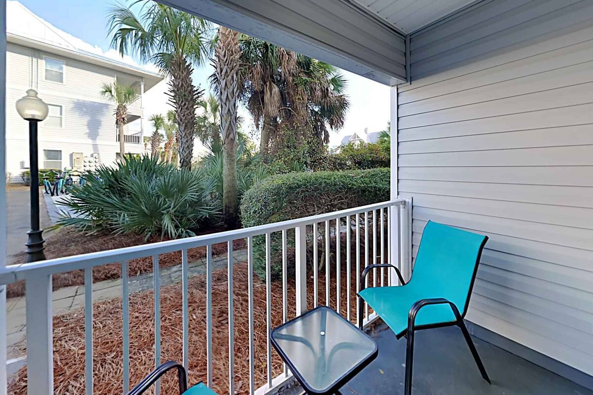 A covered outdoor area with a white railing, two chairs, and a small table.