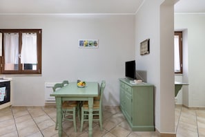 Eine Küche mit Esstisch, Stühlen, einem Schrank, einem Fernseher und einem Wandbild.