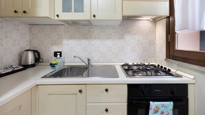 A kitchen with light wooden cabinets, a stainless steel sink, a gas stove, and a dishwasher.