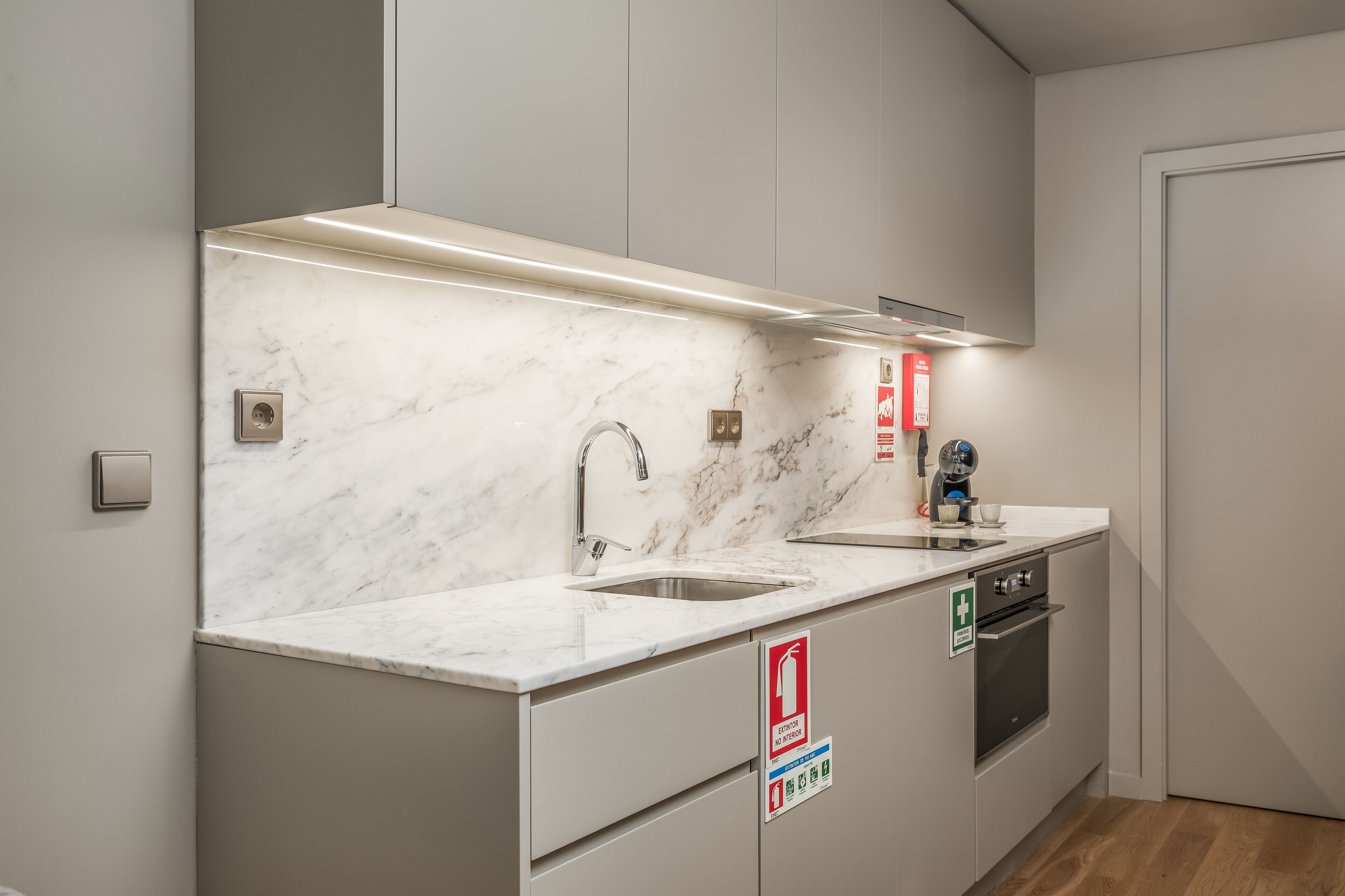 Une cuisine moderne dotée de plans de travail en marbre, d’appareils électroménagers en acier inoxydable et d’un four encastré.