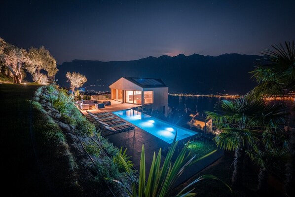 Una casa moderna con piscina, rodeada de vegetación y vistas a un cuerpo de agua.