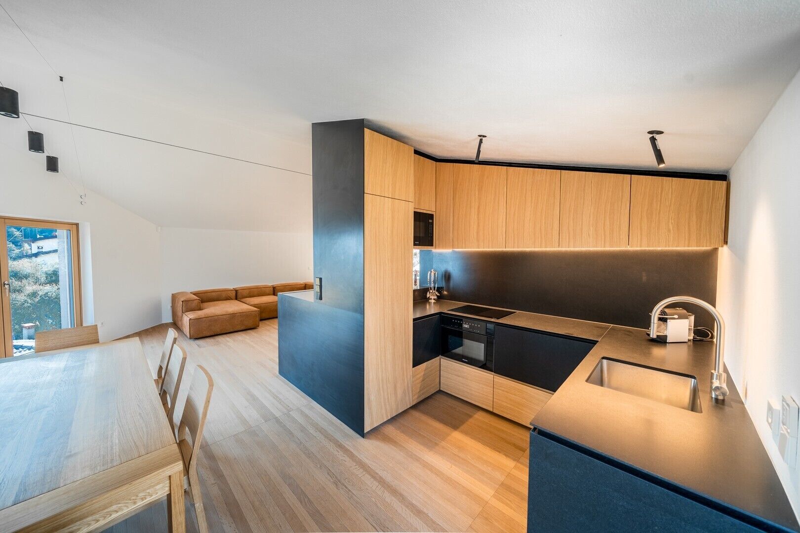 Eine moderne Küche mit Holzschränken, einem Einbauherd und einem Essbereich mit Tisch und Stühlen.