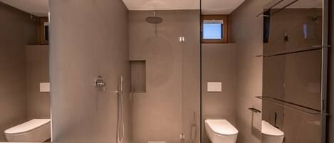 Une salle de bain moderne avec une douche à parois de verre, des toilettes et un bidet.