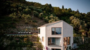 A modern two-story house with a balcony, surrounded by lush greenery and hills. - Villa Arias with Lake View, Pool, and Wi-Fi (Tremosine sul Garda)