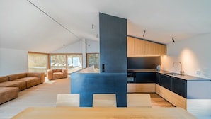 A modern kitchen with a central island, wooden cabinets, and a large window overlooking a deck. - Villa Arias with Lake View, Pool, and Wi-Fi (Tremosine sul Garda)