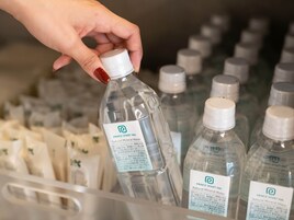 Een hand die een fles water pakt uit een dispenser met meerdere flessen.