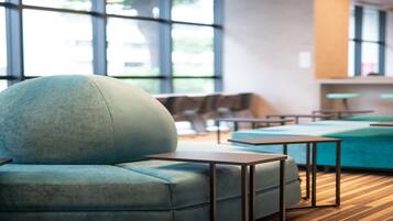 A modern lounge area with a large teal sofa, a wooden coffee table, and a teal couch.