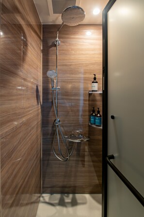 A modern bathroom with a shower, a vanity with a mirror, and a shelf with toiletries.