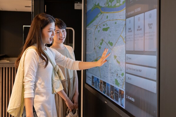 Two individuals examining a digital map display with various sections including 'Walk Around', 'Eat Around', and 'Share Trip'.