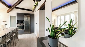 Une cuisine moderne dotée d’un four encastré, d’un coin repas avec des chaises et d’une plante en pot.