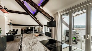 Une cuisine moderne dotée d’un plan de travail en marbre, d’un four encastré et d’une grande porte-fenêtre coulissante donnant sur un balcon.