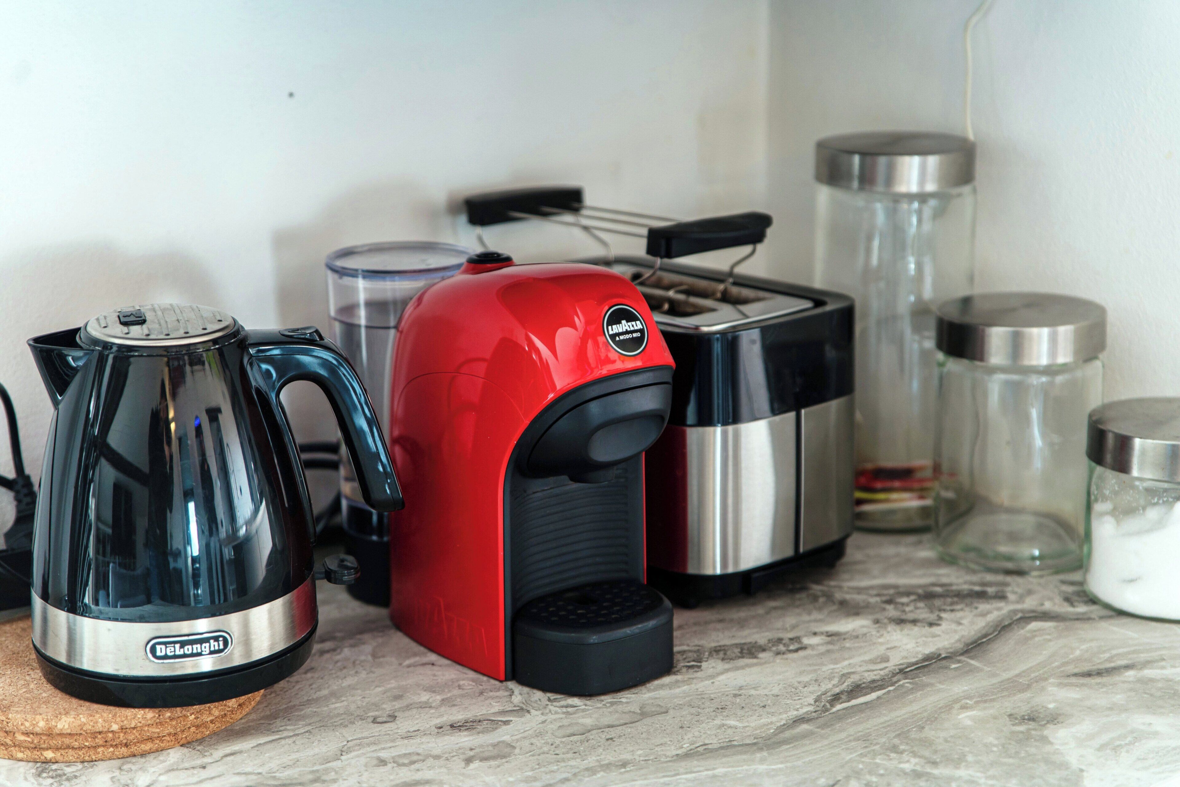 Et køkken med kaffemaskine, brødrister og beholdere på bordet.