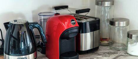 Et køkken med kaffemaskine, brødrister og beholdere på bordet.