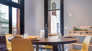 Un coin repas avec une table ronde, des chaises et une fenêtre équipée de stores.