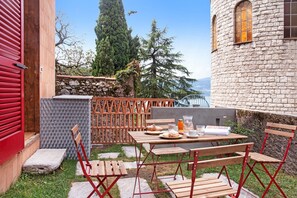 Un espace extérieur aménagé pour les repas, avec un mur en pierre, du mobilier en bois et une vue sur le paysage.