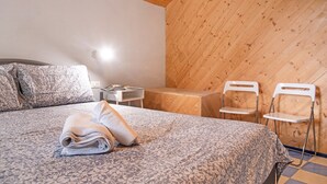 Une chambre à coucher avec un lit, des oreillers, une table de chevet avec une lampe et deux chaises blanches.