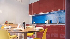 Une cuisine moderne avec des meubles de rangement rouges, un revêtement mural bleu et des chaises jaunes.