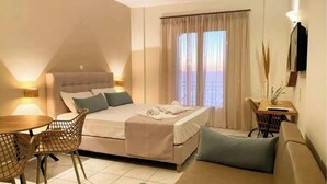 A bedroom with a bed, a sofa, a dining table, and chairs.