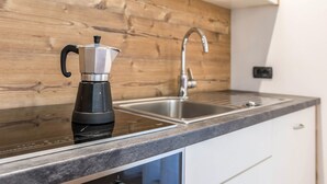 A kitchen with a coffee maker, a sink, and a wooden backsplash. - Apartment Ciasa Rosa with Mountain View, Balconies & Shared Garden (Canazei)