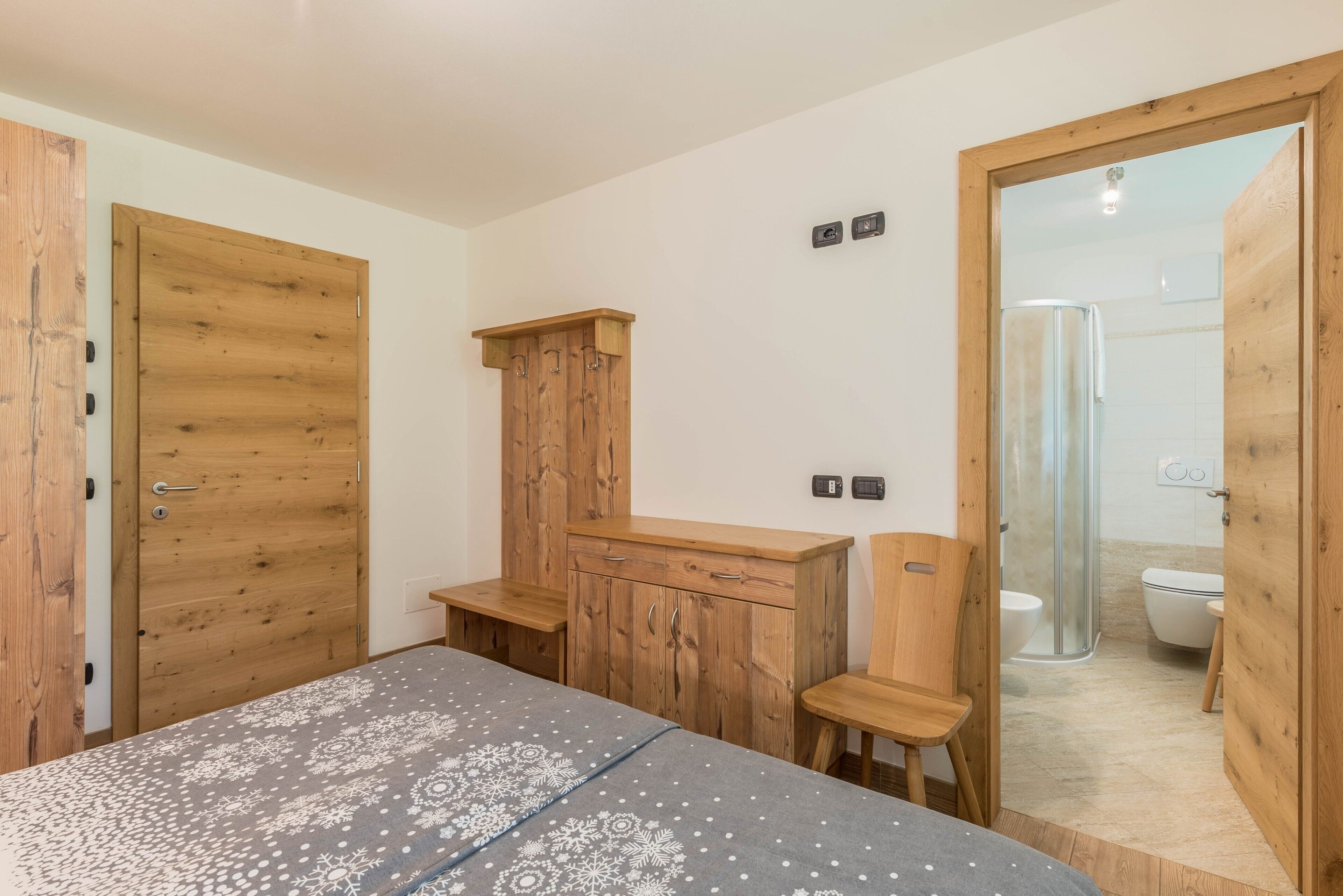 A bedroom with a bed, wooden wardrobe, a desk, and a chair.