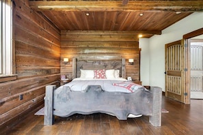 Un dormitorio de estilo cabaña de madera con cama, paredes de madera y puerta de madera.