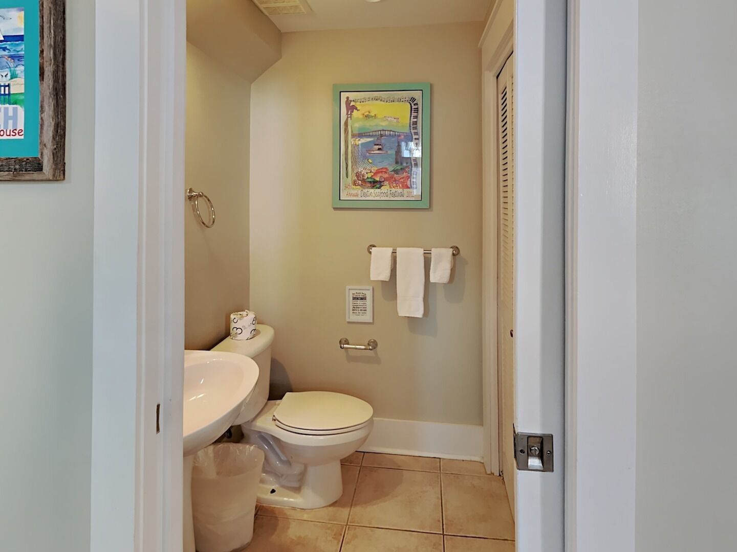 A small bathroom with a toilet, sink, and a framed picture on the wall.