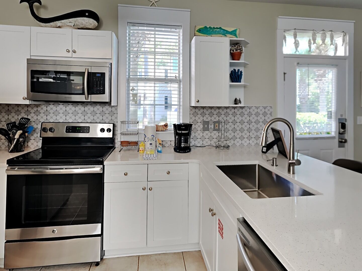 A modern kitchen with white cabinetry, stainless steel appliances, and a large island with a sink.