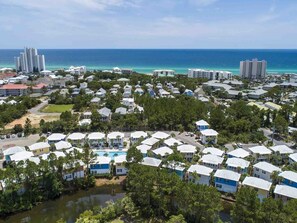 A coastal residential area with multiple-story buildings, a marina, and a clear view of the ocean.