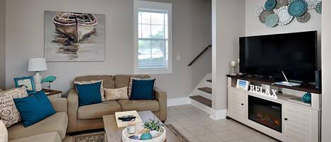 A living room with a beige sofa, a coffee table, a TV, and a fireplace.