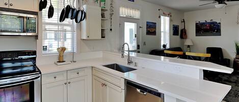A modern kitchen with white cabinetry, a built-in dishwasher, and a large island.