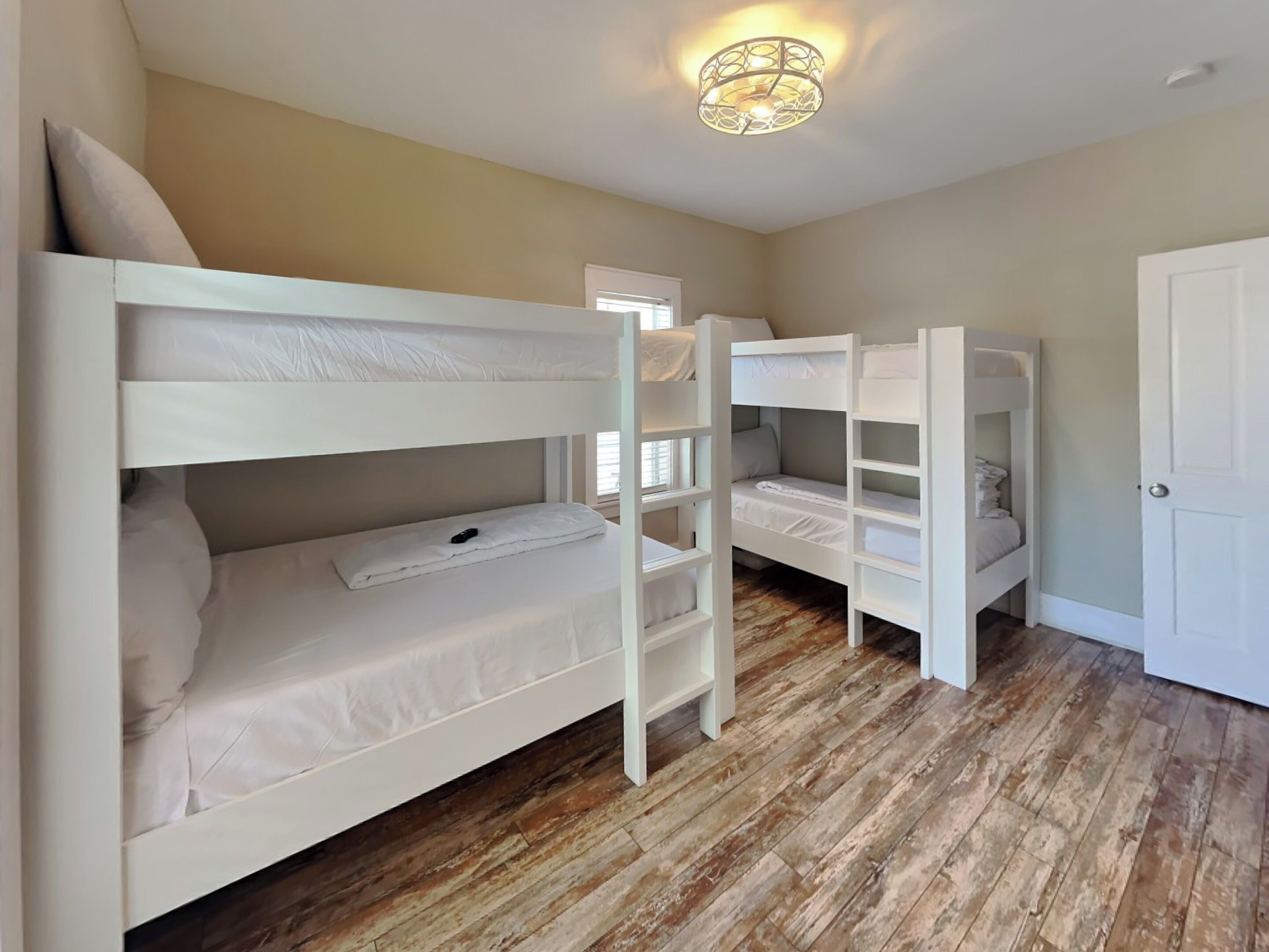 A room with bunk beds, a wooden floor, and a door.