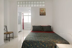 Un dormitorio con una cama, una silla, un escritorio y un cuadro en la pared.
