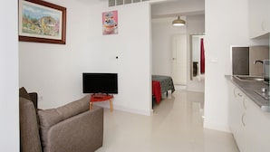 A living room with a sofa, a flat-screen TV, and a painting on the wall.