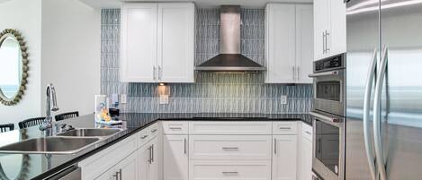 A modern kitchen with white cabinets, stainless steel appliances, and a patterned backsplash.