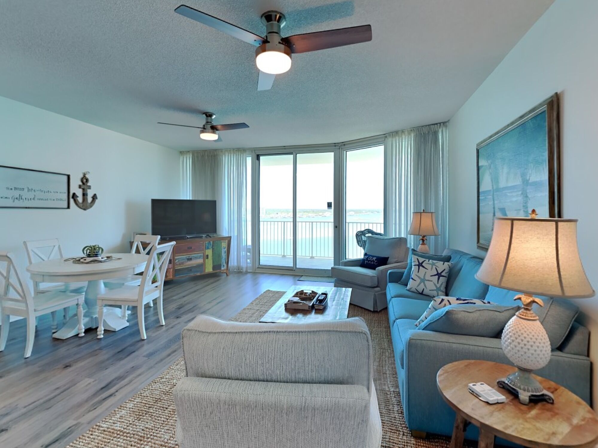 A spacious living room with a television, dining area, and a balcony with a view.