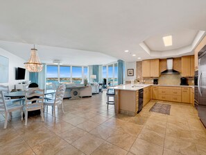 Une cuisine moderne dotée d’un grand îlot central, de meubles en bois et offrant une vue sur la mer.