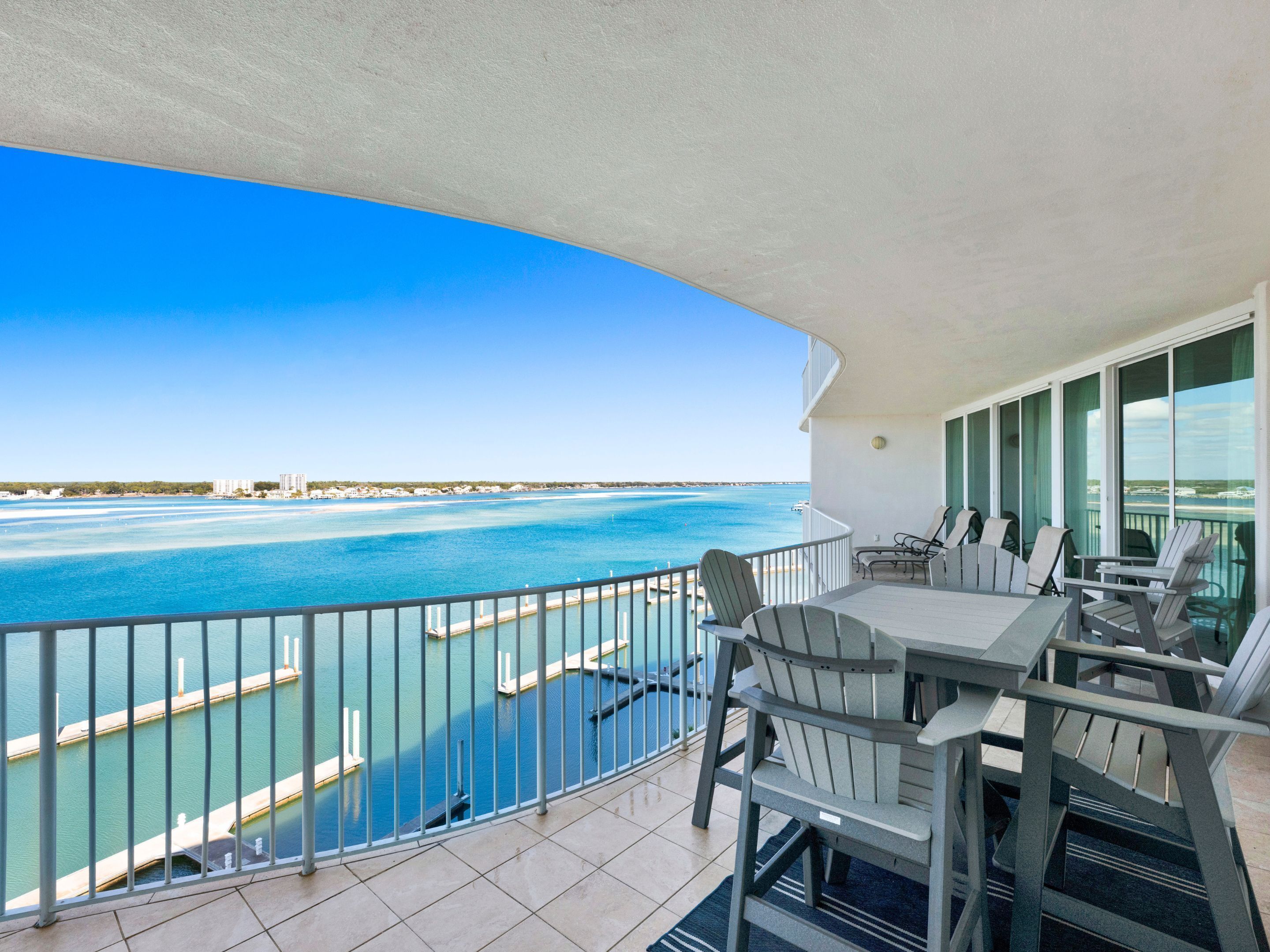 A balcony with a view of the sea, a table, and chairs.