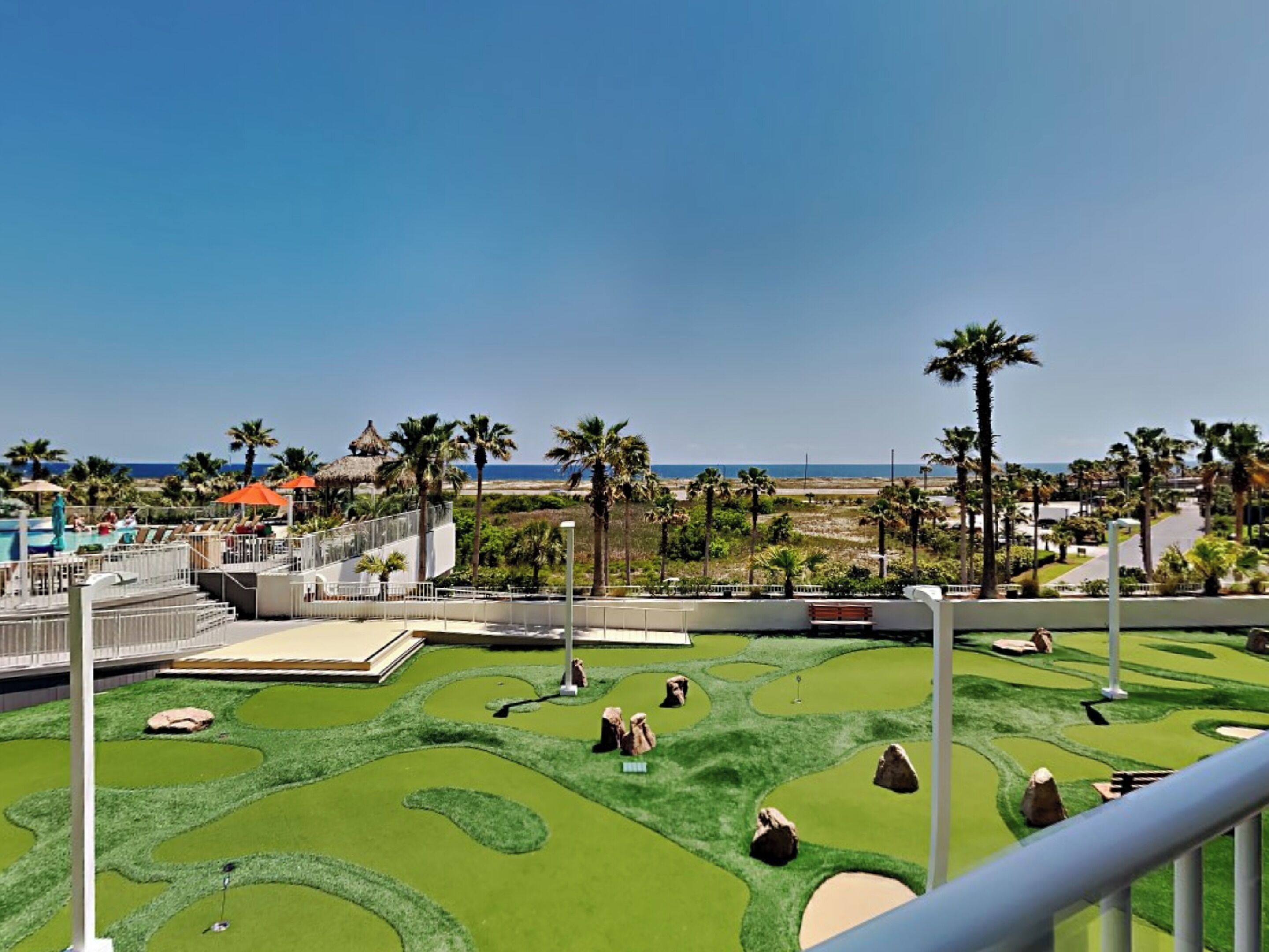 Campo de golf con vista a la playa y palmeras.