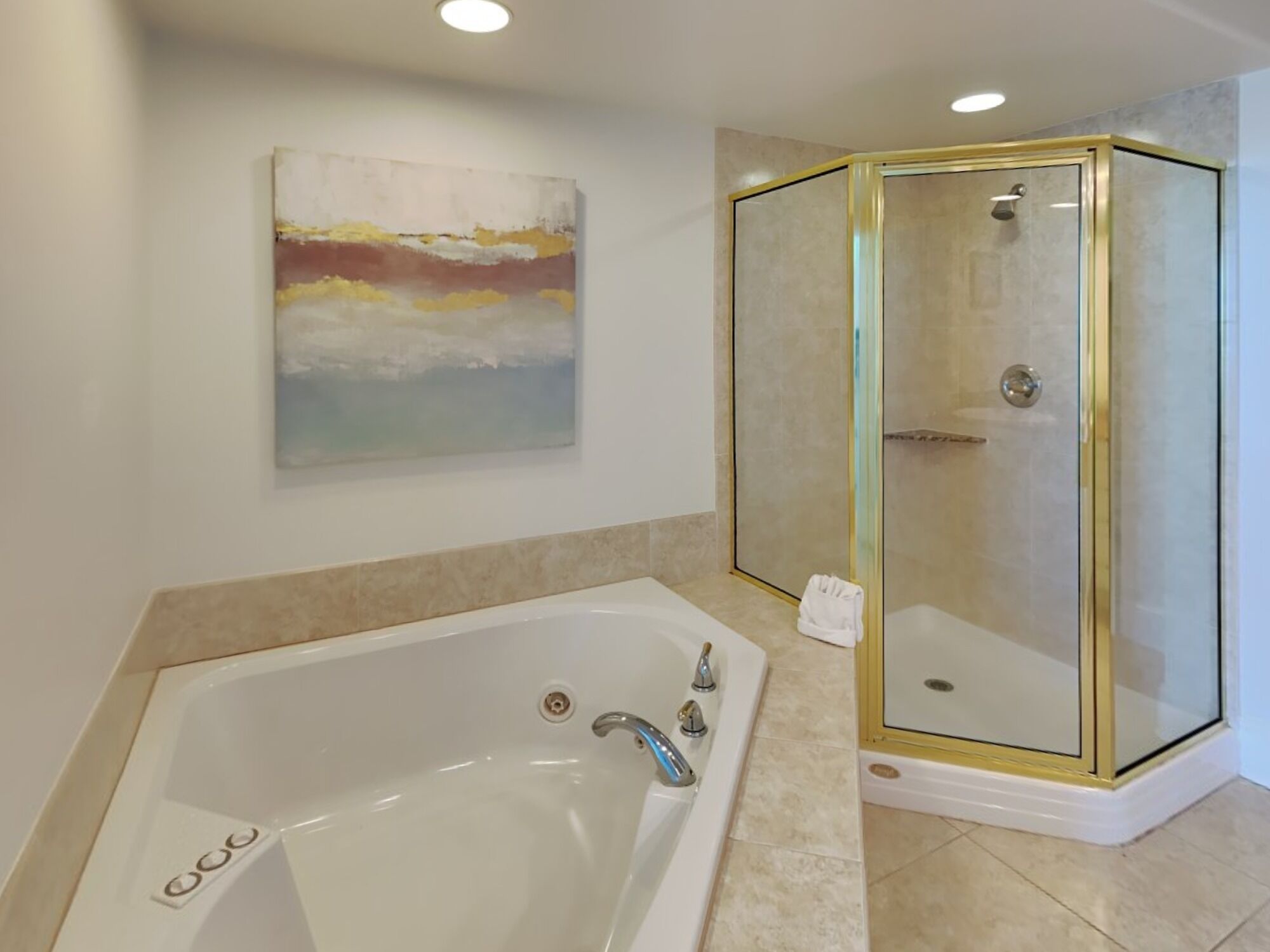 A modern bathroom with a large bathtub, a glass-enclosed shower, and a painting on the wall.