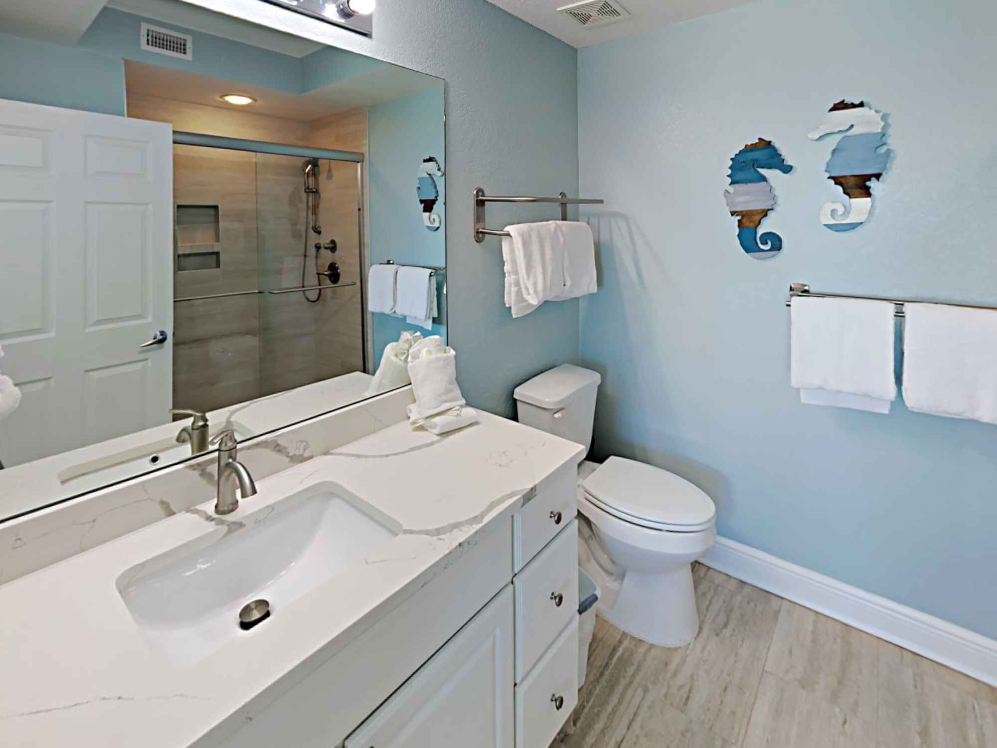 A bathroom with a sink, mirror, towel rack, toilet, and shower.