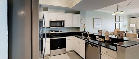 A modern kitchen with white cabinets, stainless steel appliances, and a black countertop.