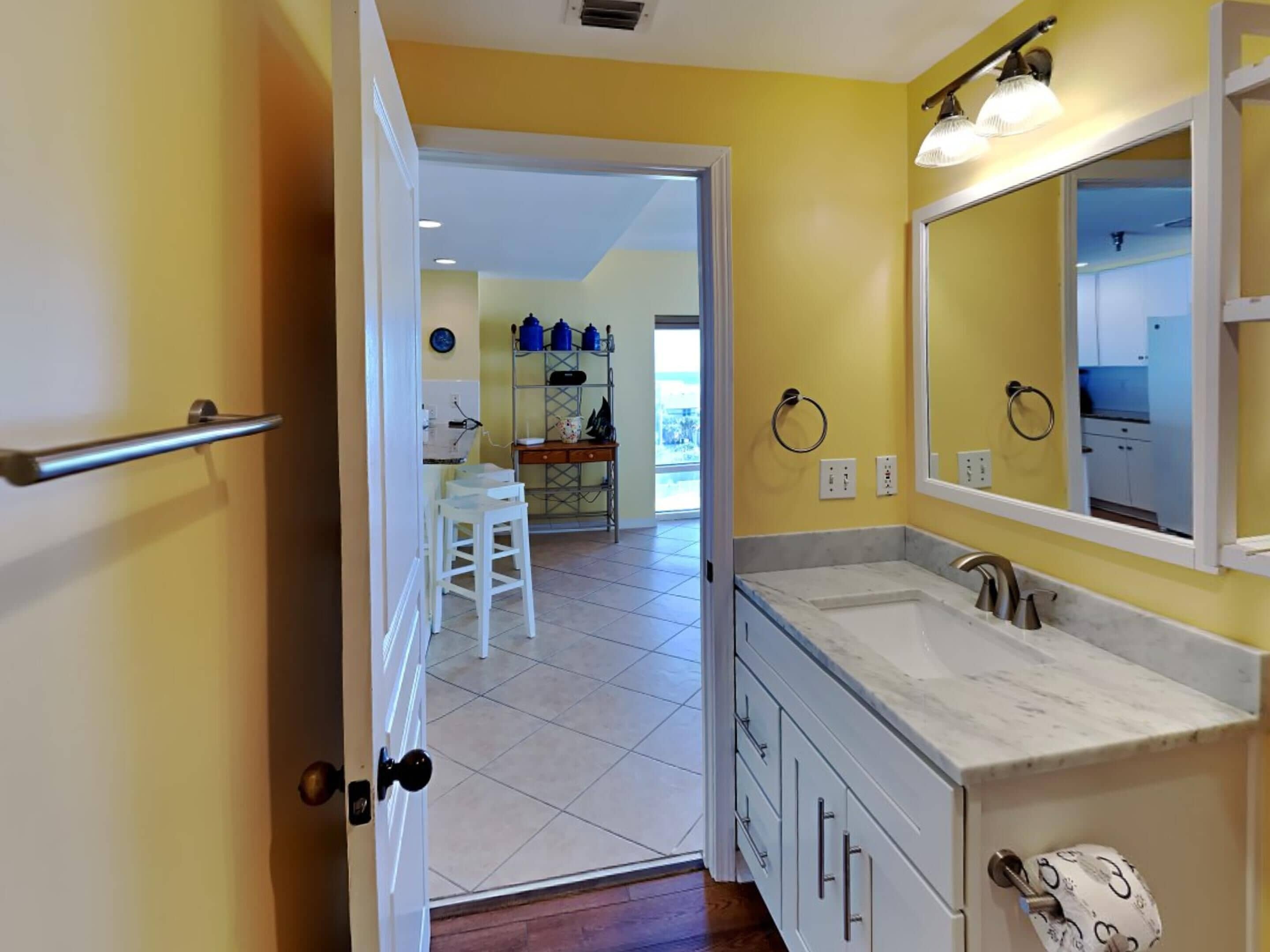 A bathroom with a white sink, a mirror, and a toilet paper holder.