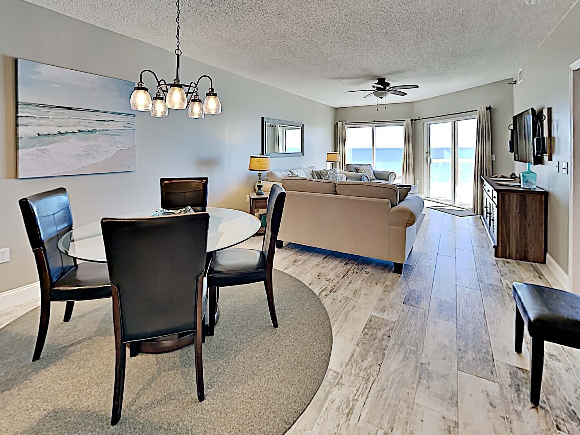 A spacious living area with a dining table, chairs, a sofa, and a ceiling fan.
