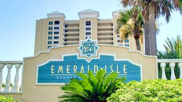 A resort sign with a palm tree in the foreground.