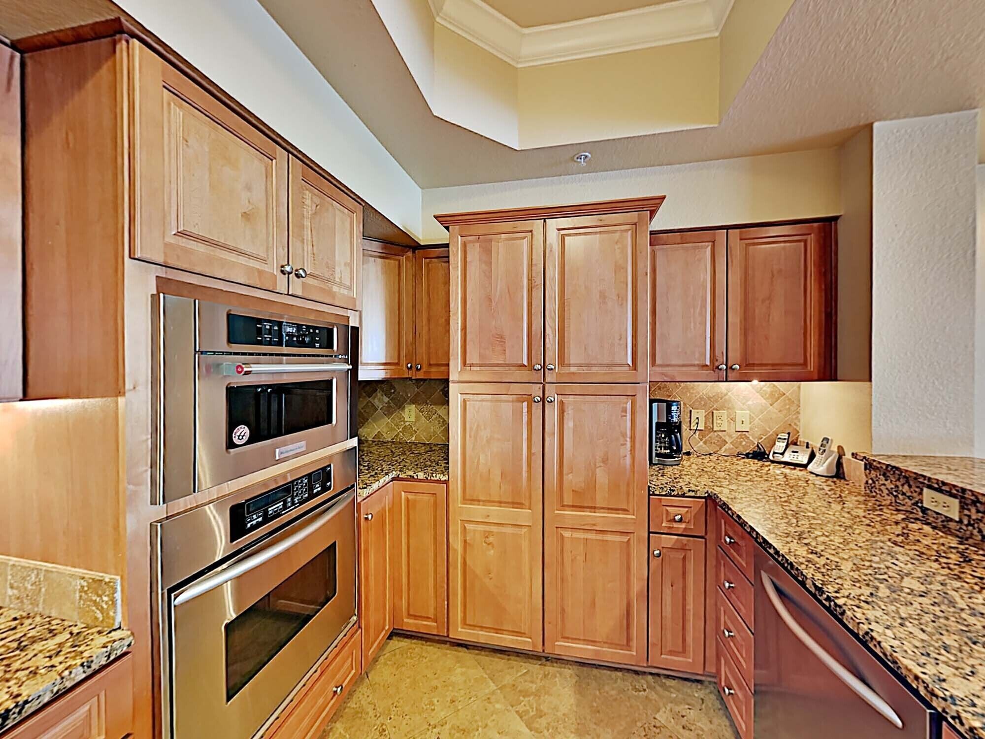 A kitchen with wooden cabinets, a built-in oven, and granite countertops.