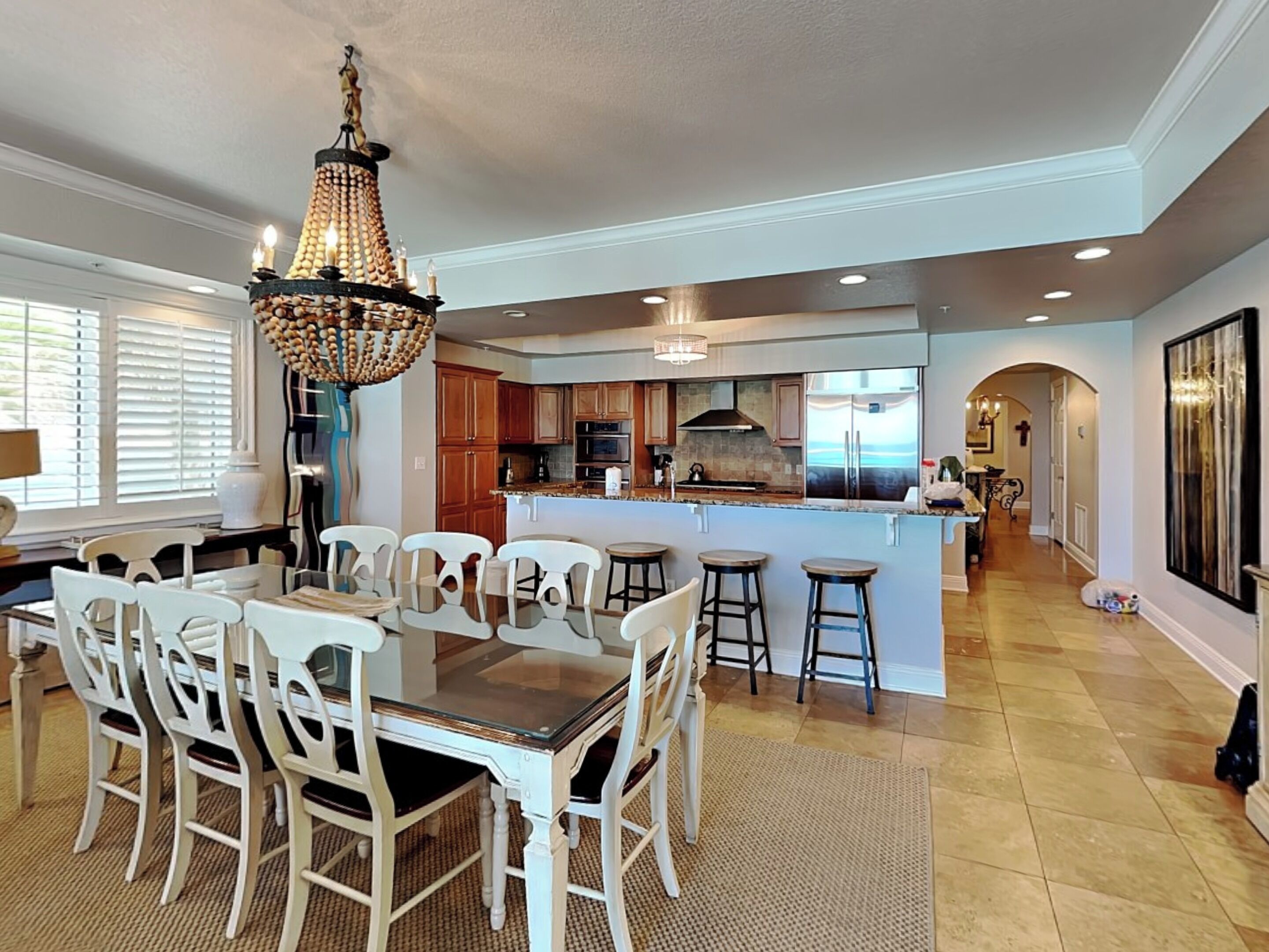 A spacious kitchen with a central island, wooden cabinets, and a chandelier.