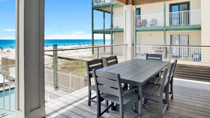 Een houten terras met tafel en stoelen met uitzicht op een strand.