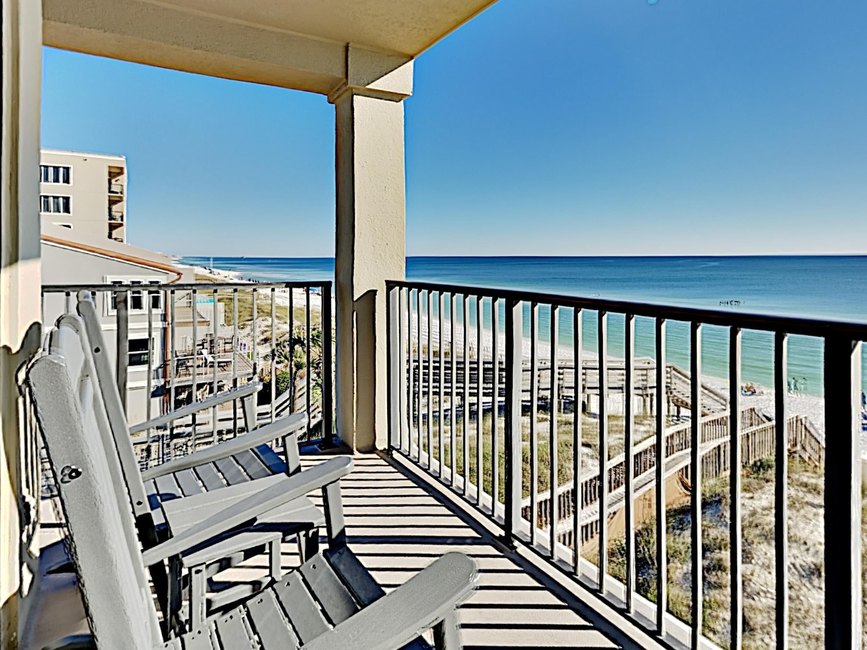 A balcony with a view of the beach and ocean.