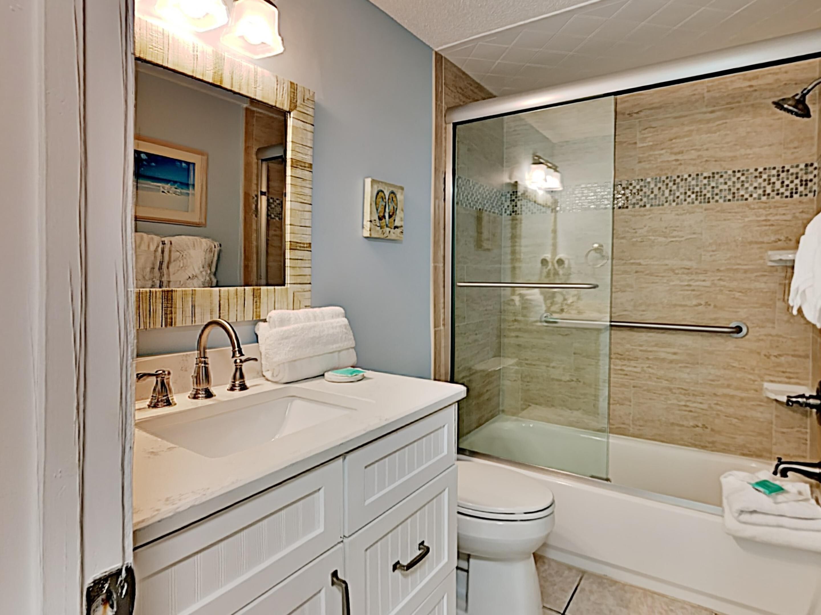A bathroom with a white sink, a mirror, a toilet, and a glass-enclosed shower.