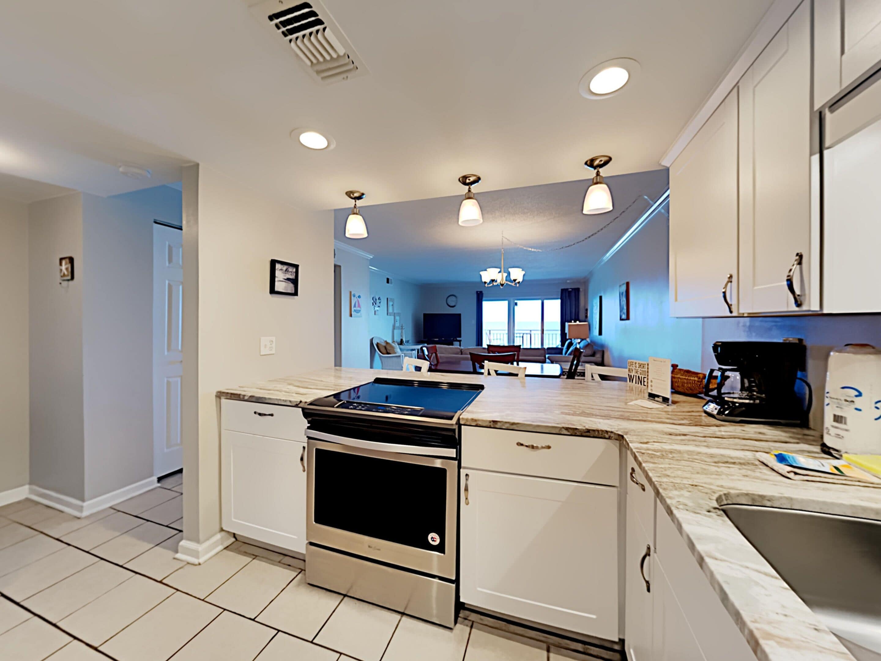 A modern kitchen with a central island, built-in oven, and white cabinetry.